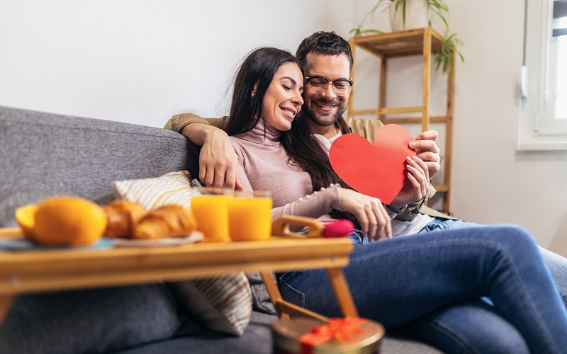 A couple sitting at table with a heart card and breakfast